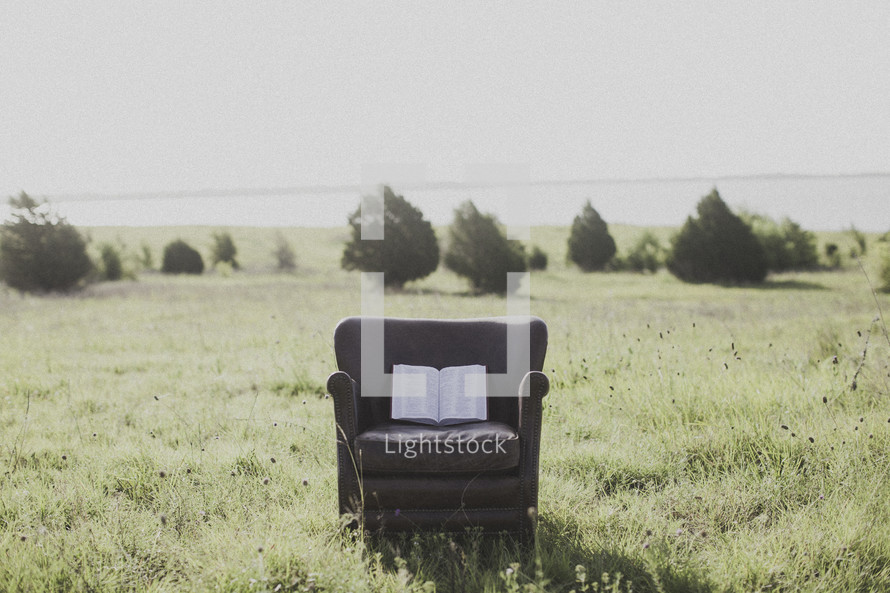 an open Bible in a chair in a field 