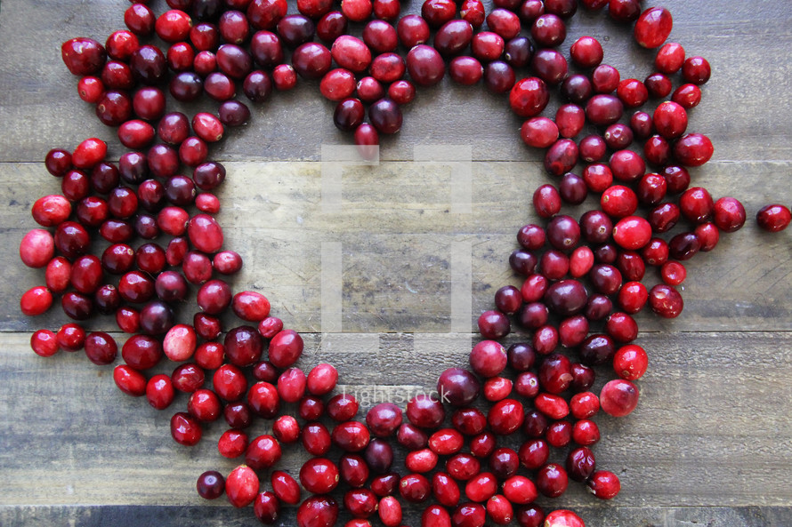 Cranberries in the shape of a heart on a wooden background
