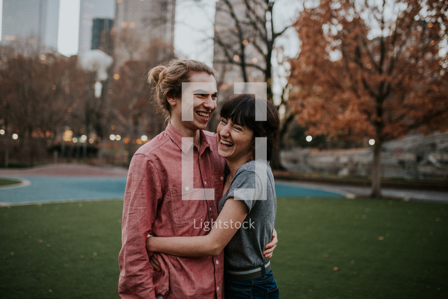 a happy couple standing together in a city park 