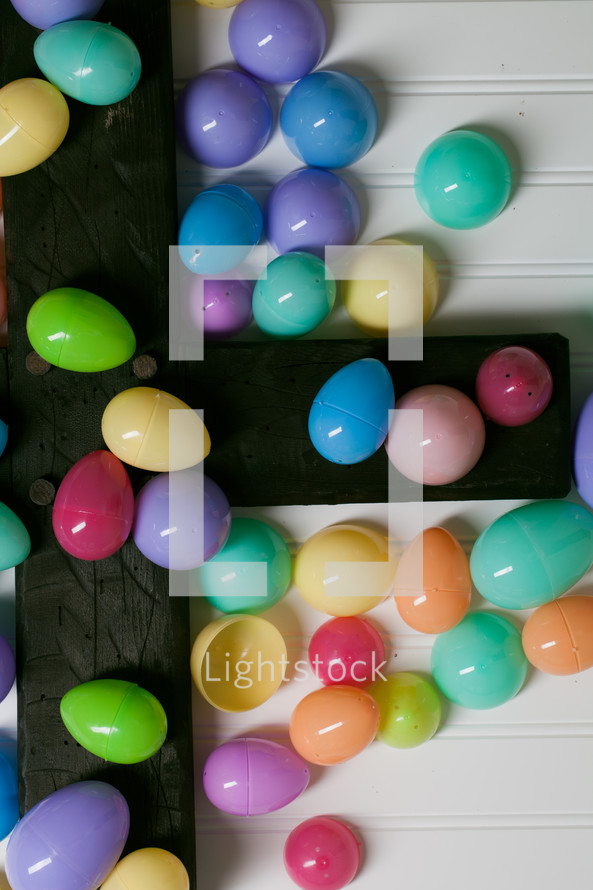 Colorful plastic Easter eggs on a wooden cross.