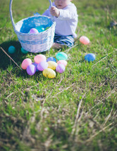 toddler playing with an Easter basket in the grass