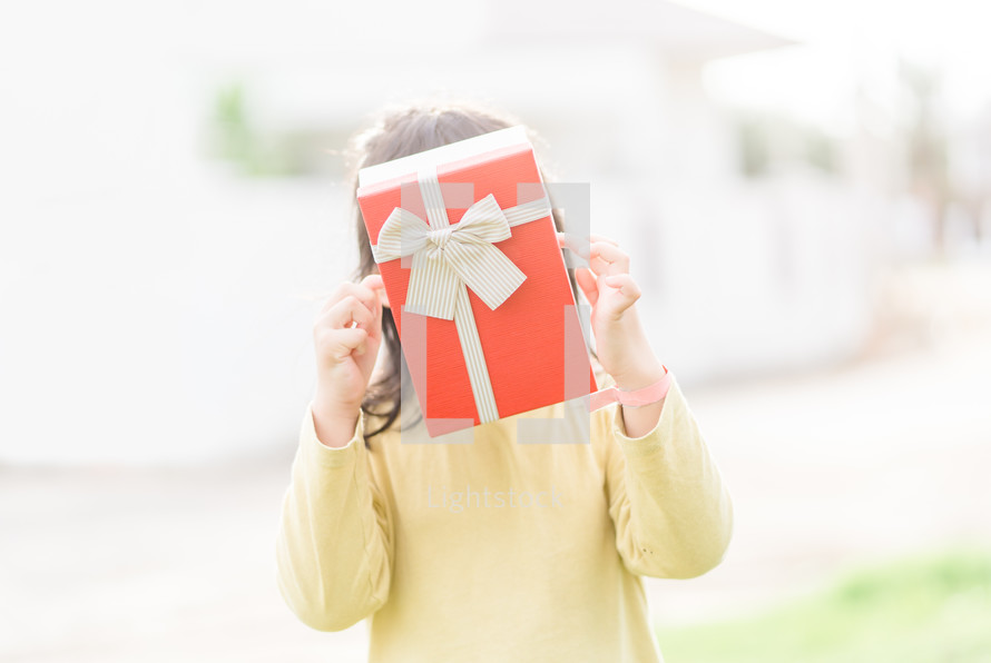a child holding a red Christmas gift 