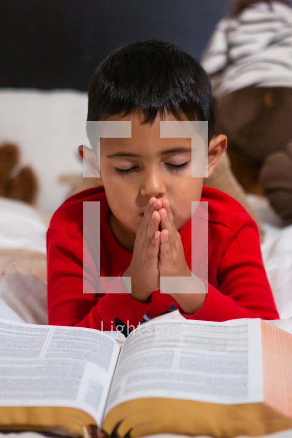 child reading a Bible in bed 
