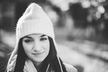 A young woman smiling and wearing a white beanie