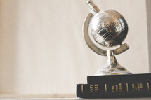 brass globe paper weight on a stack of books 