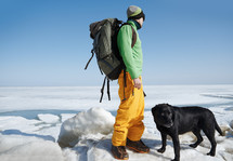 man hiking with his dog through snow 