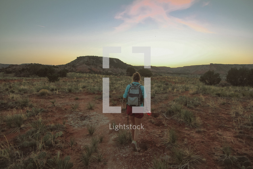 a woman backpacking through a desert landscape 