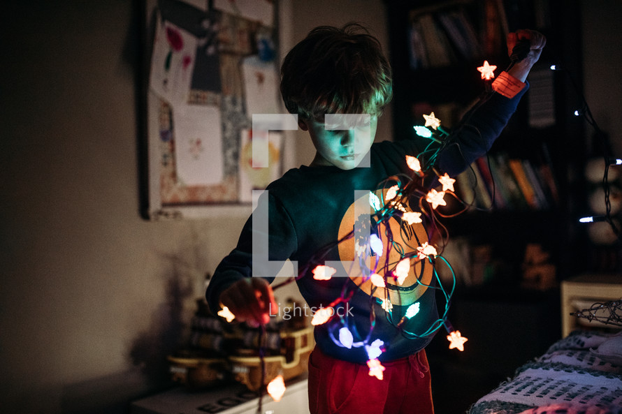 child holding a strand of Christmas lights 