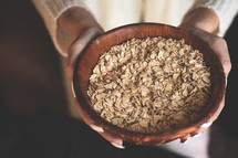 a woman holding a bowl of oats 