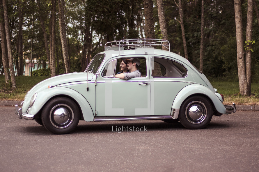 a couple driving in a vintage Volkswagen Beetle 