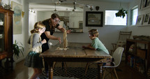 mother and children doing a science experiment in the dining room 