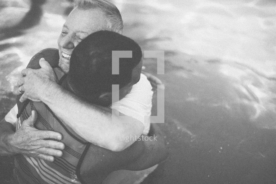 Two men hugging in a pool of water.