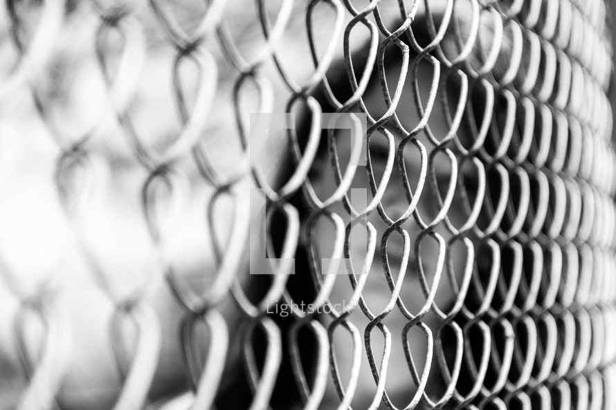 face of a woman behind a chain link fence 