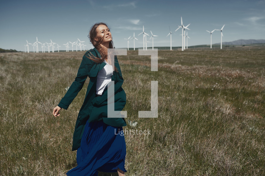 a woman standing in front of a wind farm 