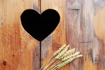 Heart shape cut out in wood background with wheat 