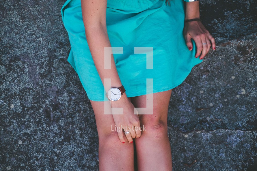 woman's legs sitting on the ground in a teal skirt