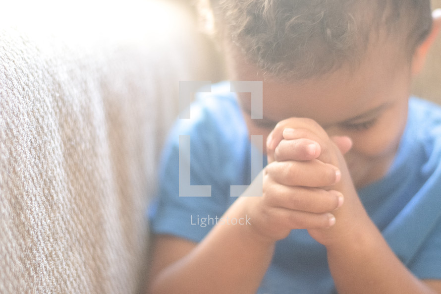 a toddler with praying hands 