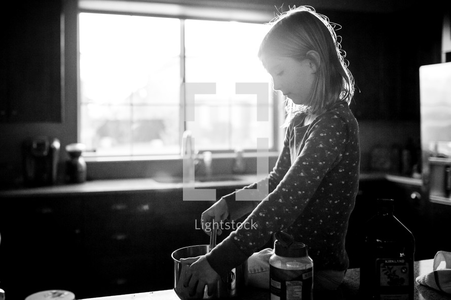 a little girl stirring a bowl in a kitchen 