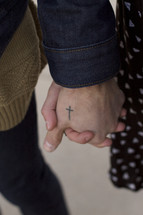 a couple holding hands - cross tattoo 