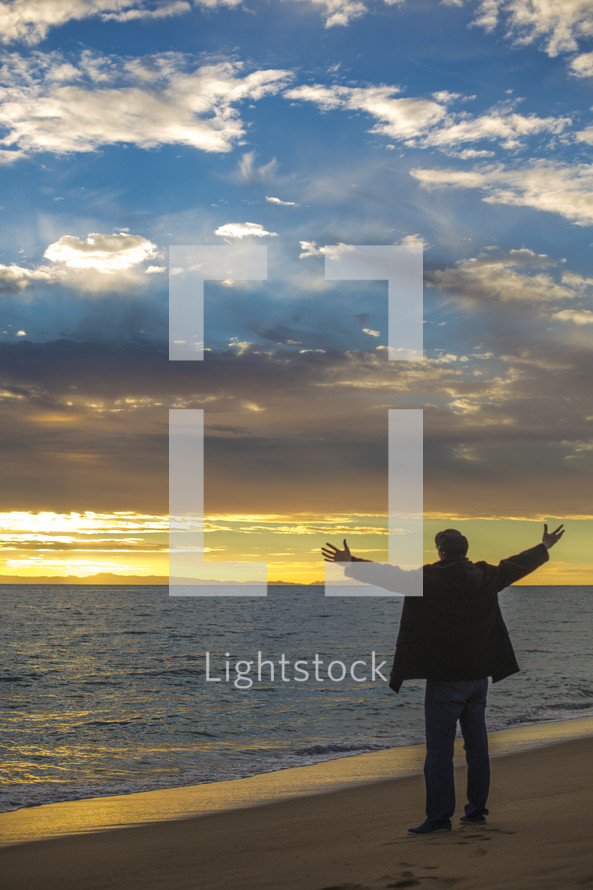 man with open arms on a beach 