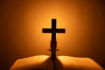 Candlelight photo of a Bible and cross