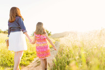 mother and daughter walking holding hands carrying a Bible