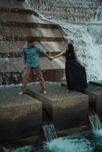 couple standing on a fountain holding hands 