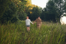 blurry image of a couple walking holding hands through tall grass