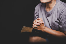Woman praying with folded hands on a Bible
