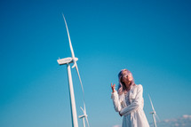 woman standing beside wind turbines 