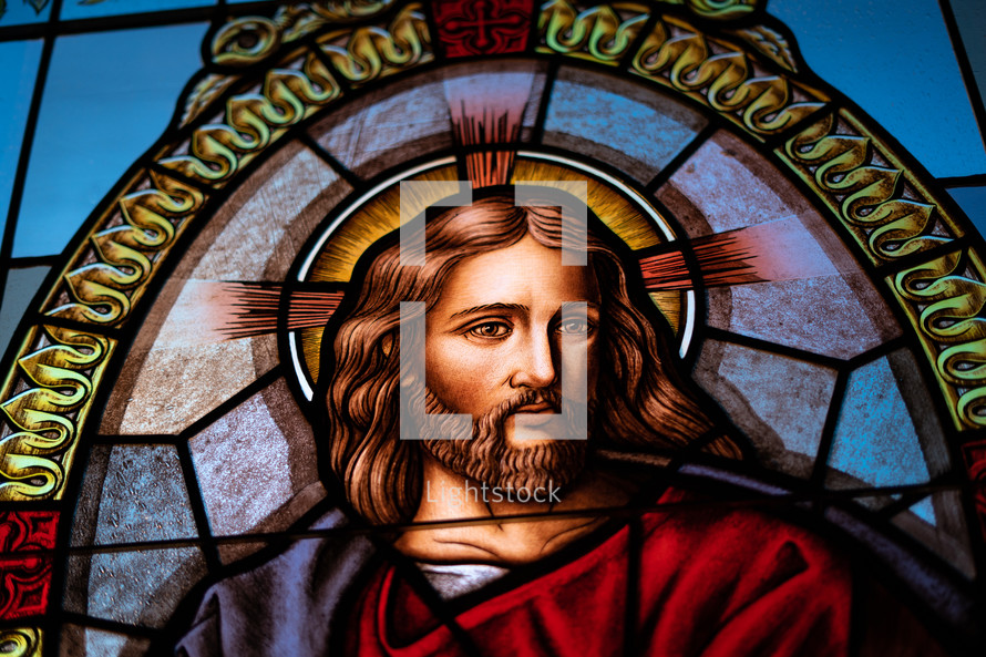 Close up of a stained glass window showing Jesus alight with compassion.