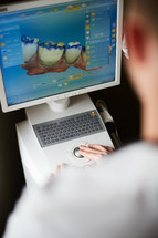 a dentist looking at computer scans of teeth 