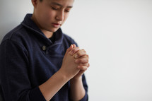 boy with head bowed in prayer