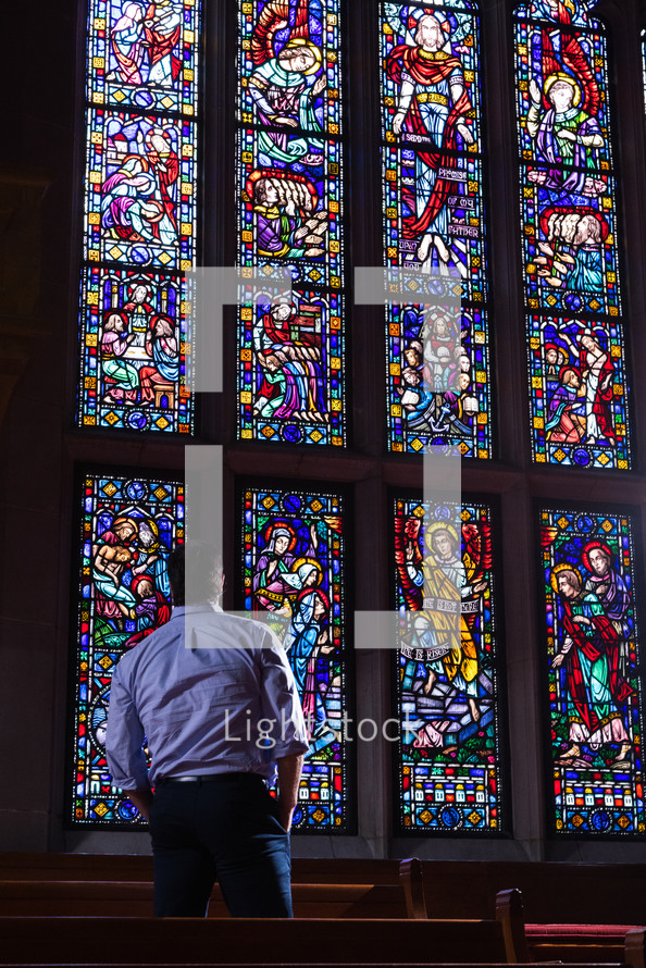 a man standing in front of a stained glass window 