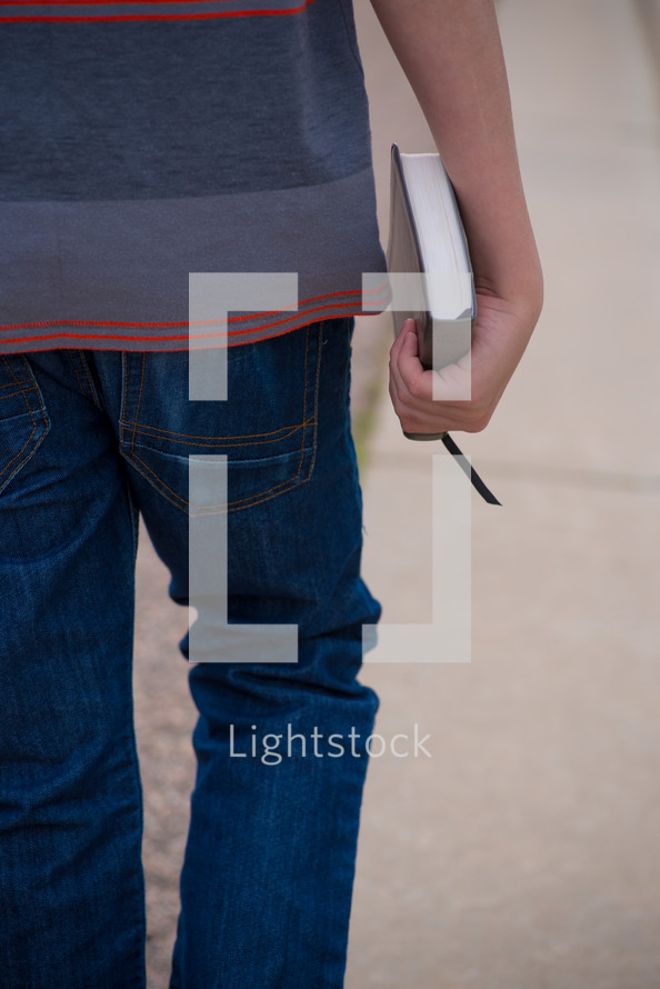 teen boy carrying a Bible 