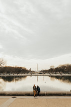 couple sitting with a view of the Washington monument behind them 
