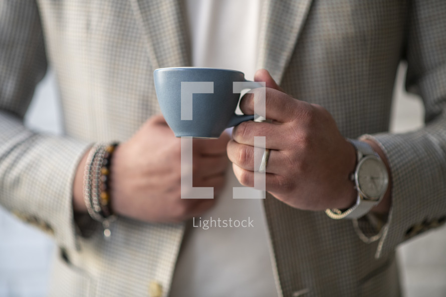 a man in a suit holding a tea cup 