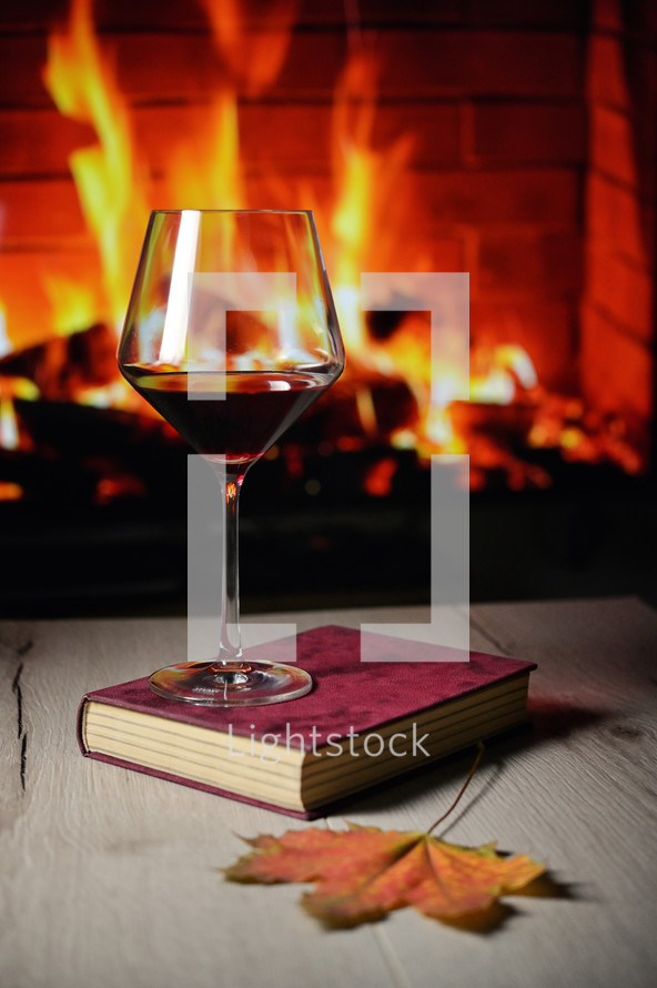 Dry Glass Of Red Wine, on Book and Fireplace in Background