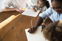 children coloring at the kitchen table with mom and dad 