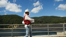 Engineer with white helmet holds a project of the new dam