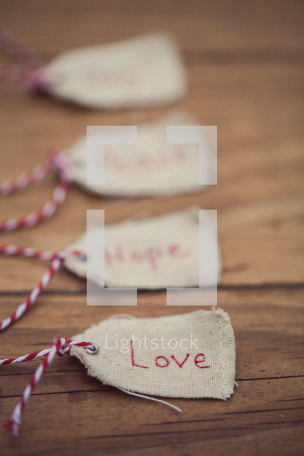 Christmas gift tags on a wood grain background, the first one reading "Love."