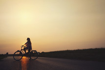 woman riding a bicycle at sunset 