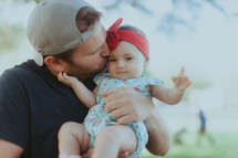 a father kissing his infant daughter 