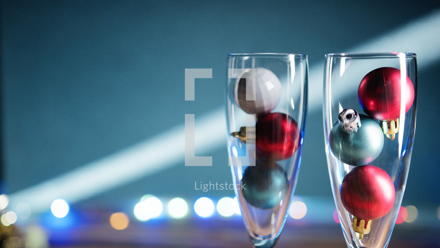 Glasses filled with Christmas balls under flashing lights 