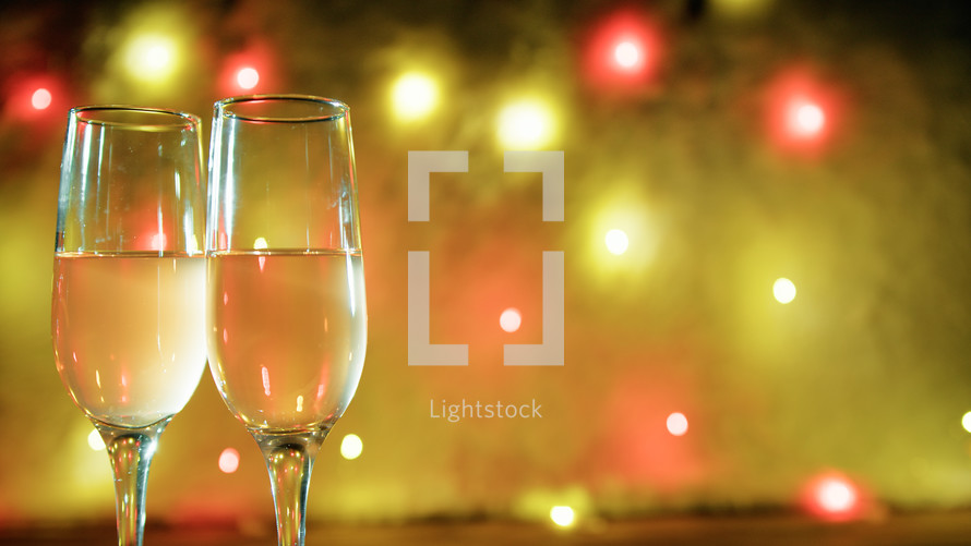 Sparkling wine glasses with disco lights in the background 