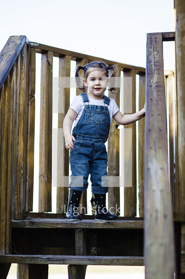 Little girl standing at the top of wooden stairs