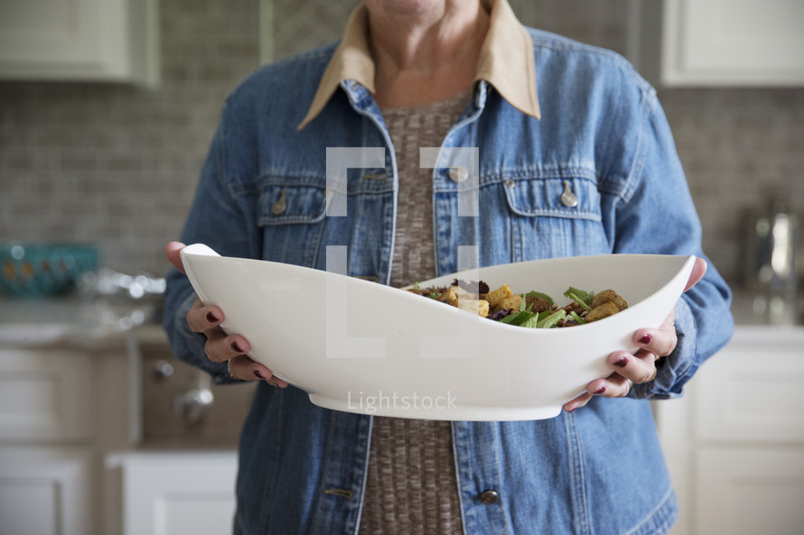 a woman holding a large salad 