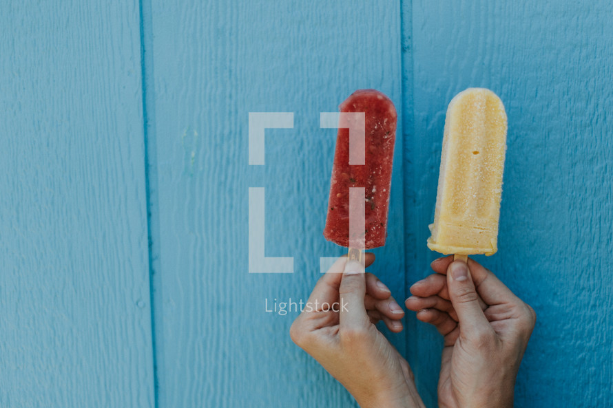 hands holding up popsicles 