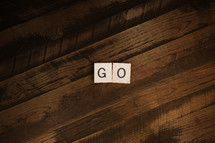 The word "go" spelled out in scrabble letters on wood background