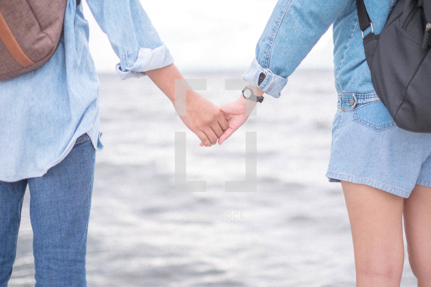 a couple holding hands on a shore 